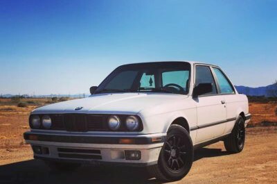 White 1980's 2 door bmw on dirt road
