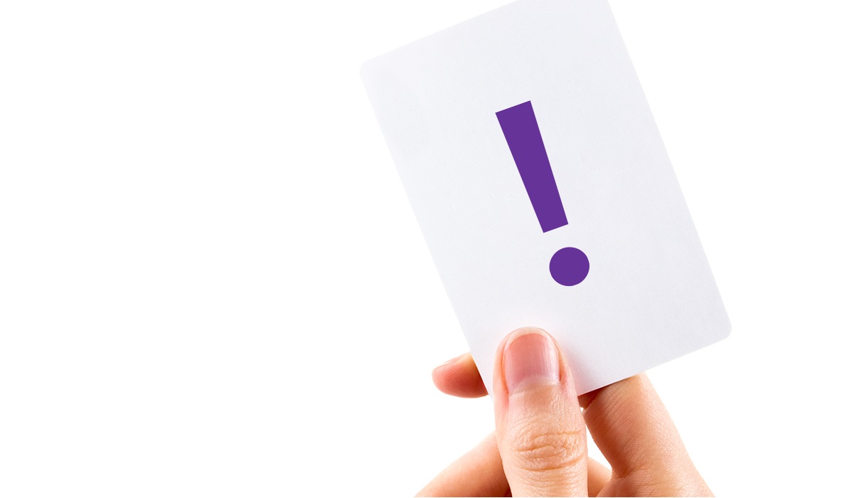 Hand holding white card with purple exclamation mark on it
