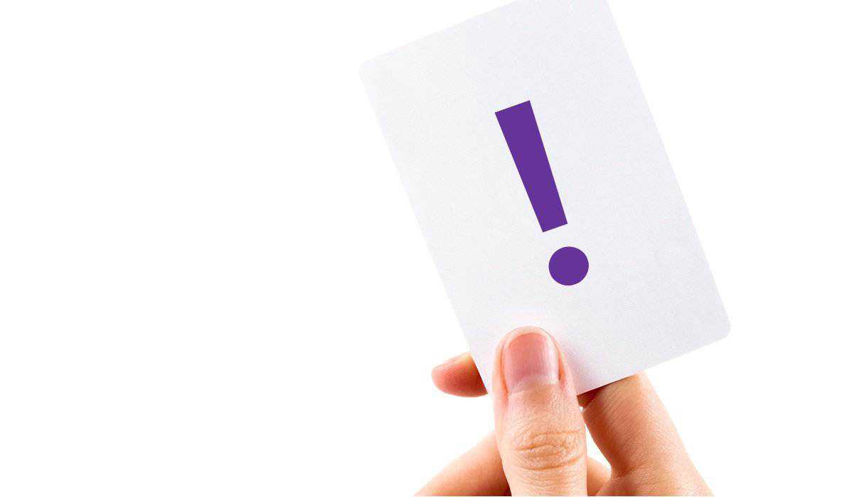 Hand holding white card with purple exclamation mark on it