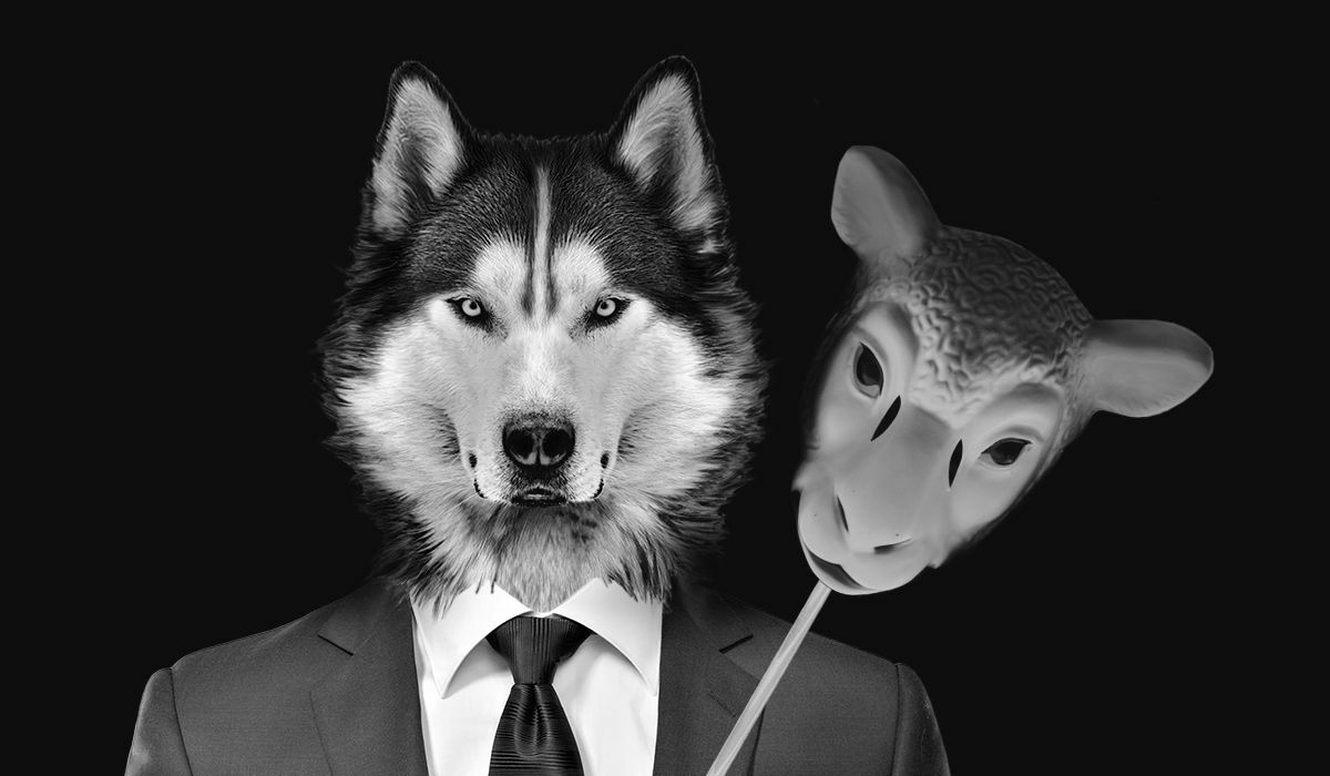 Wolf in suit and tie holding mask of sheep