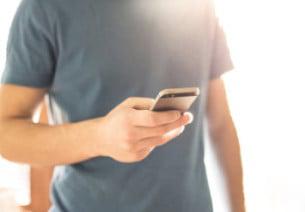Male torso blue shirt holding cell phone