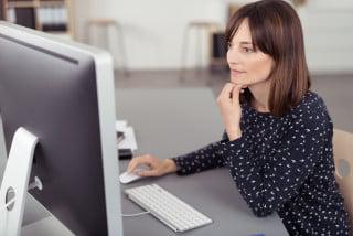 Woman sitting at desktop computer holding her chin