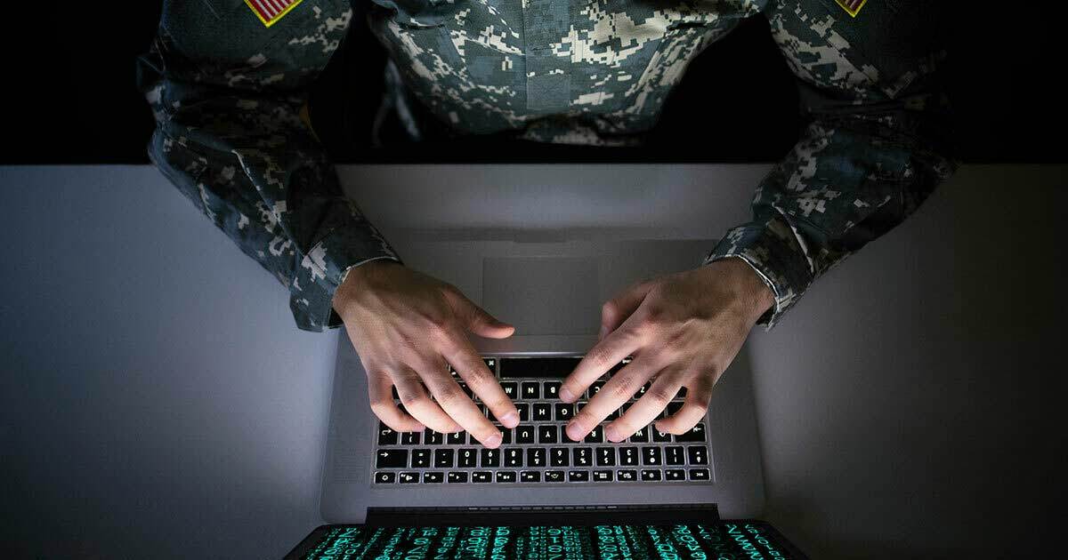 Man in military fatigues typing at laptop