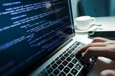 Hand typing on keyboard with coffee cup
