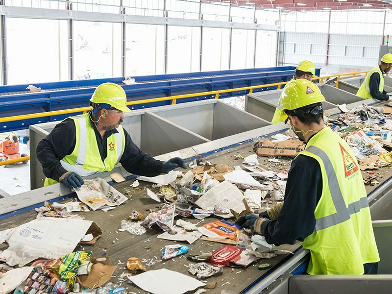 Two men in factory sifting through garbage on a conveyor belt. Republic Services Chooses Cosmos (formerly CAST) for Continuous Testing that Scales.